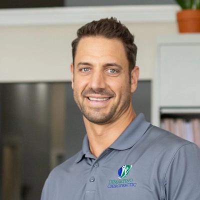 Chiropractor Eric DiMartino smiling in a grey shirt.