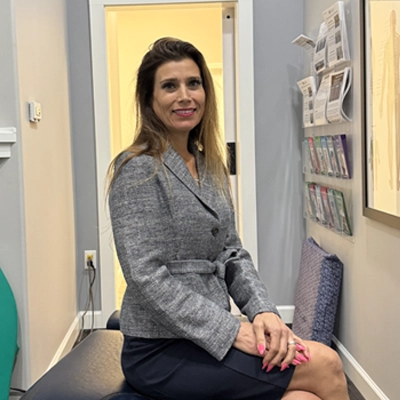 Chiropractor Angela DiMartino smiling while sitting on an adjustment table.